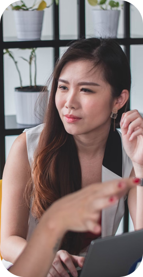 Woman looks thoughtfully at hand pointing at laptop | Offshore Outsourcing | Parallel Outsourcing