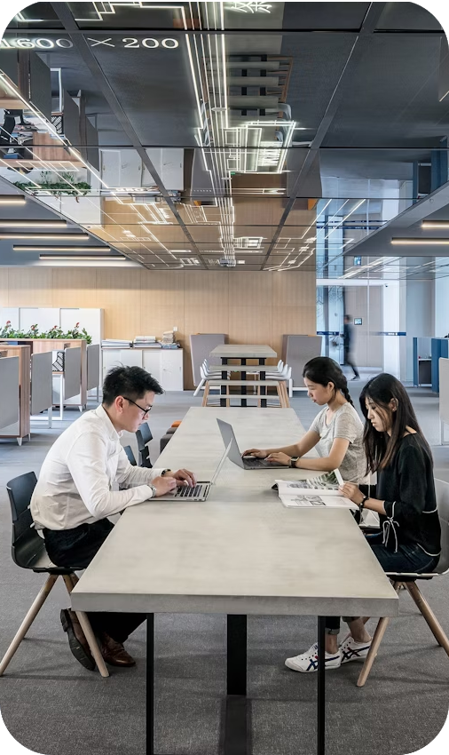 Three people working on laptops at a modern office table | It Outsourcing | Parallel Outsourcing